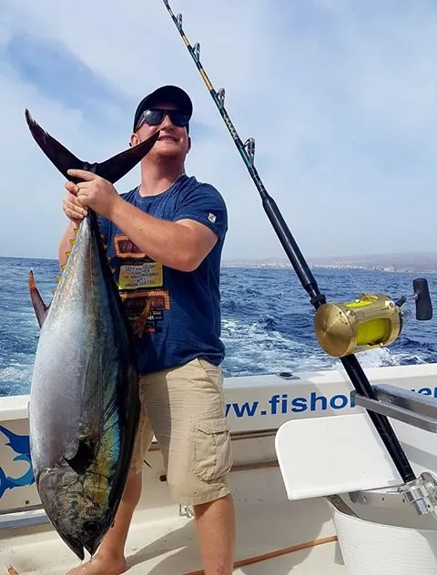 Angler lifting a tuna by the tail