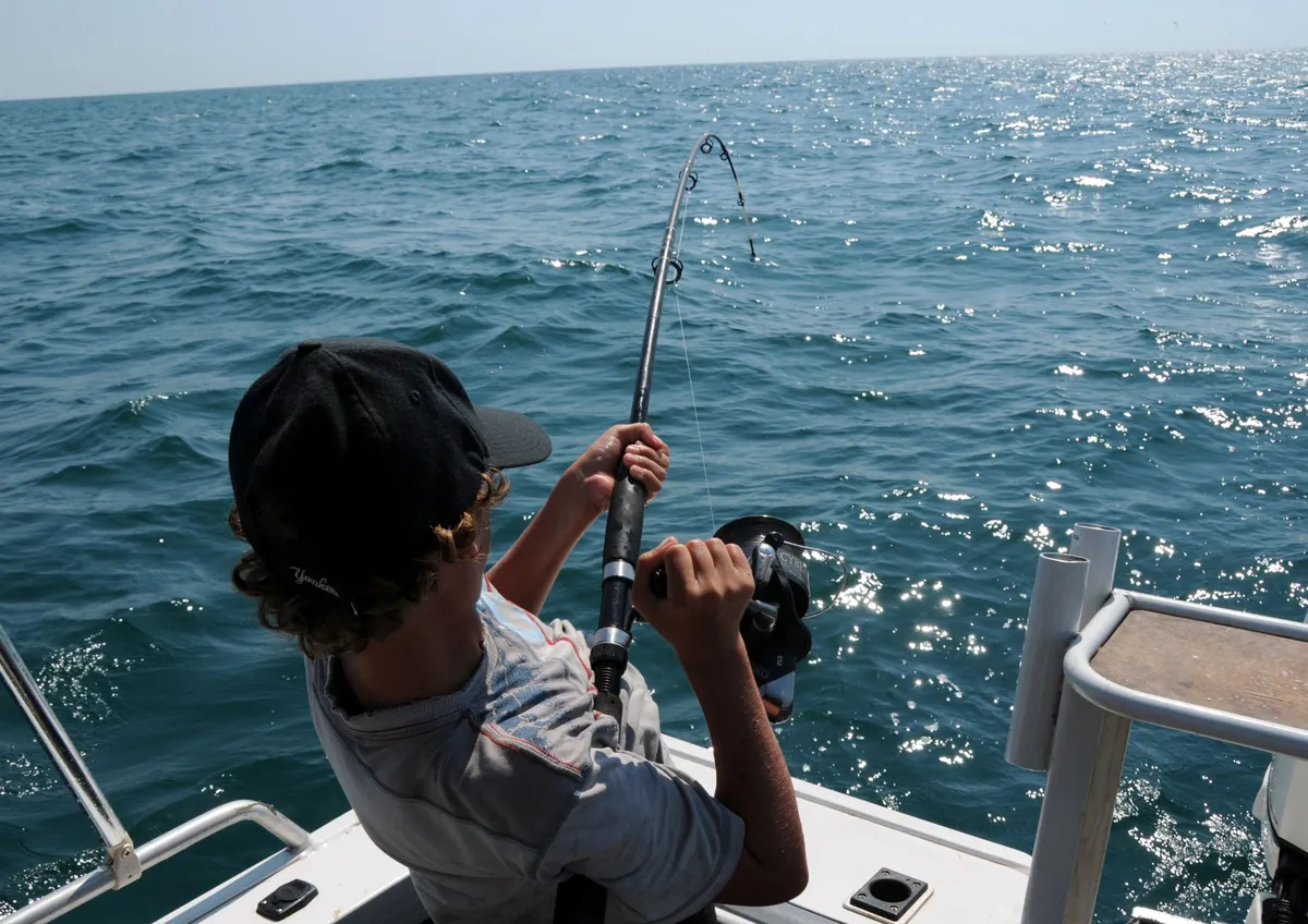 Boy fighting a fish with a rod on the back deck