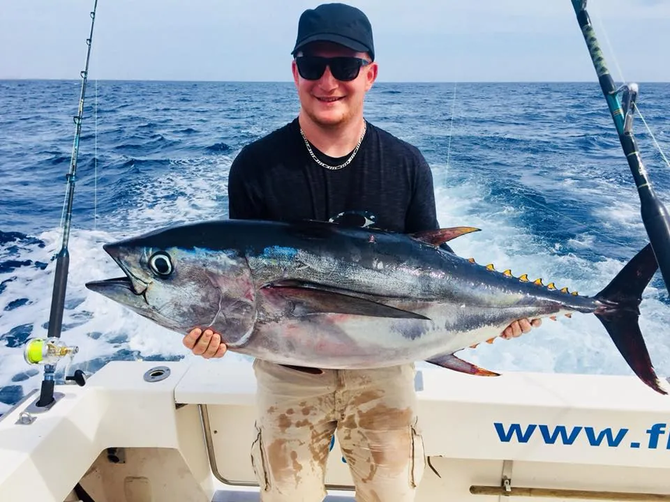 Angler holding a large tuna on the deck of Fish On!